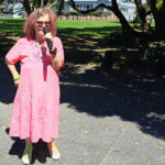 Tessa, mic in hand, stands in front of the glade in Coyle Park where we like to perform.